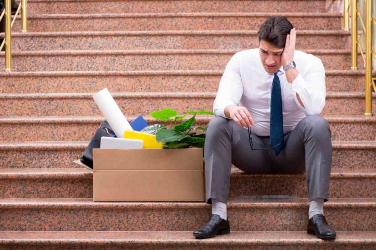 uomo triste seduto sulle scale con accanto uno scatolone