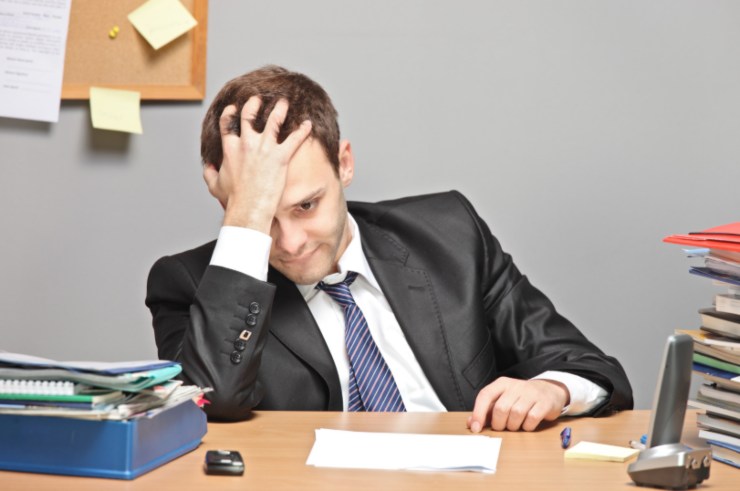 uomo seduto alla scrivano con una mano sulla testa