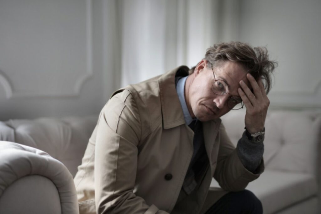 uomo preoccupato seduto sul divano con una mano sulla fronte