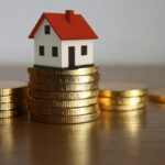 casetta in miniatura sopra una pila di monete