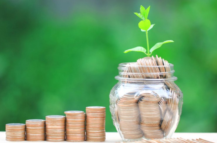 barattolo pieno di monete e accanto delle pile di monete