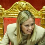giorgia meloni che sorride seduta in parlamento