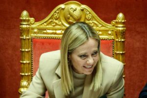 giorgia meloni che sorride seduta in parlamento