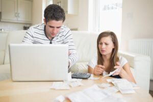 uomo e donna con espressione preoccupata davanti al computer che controllano dei fogli