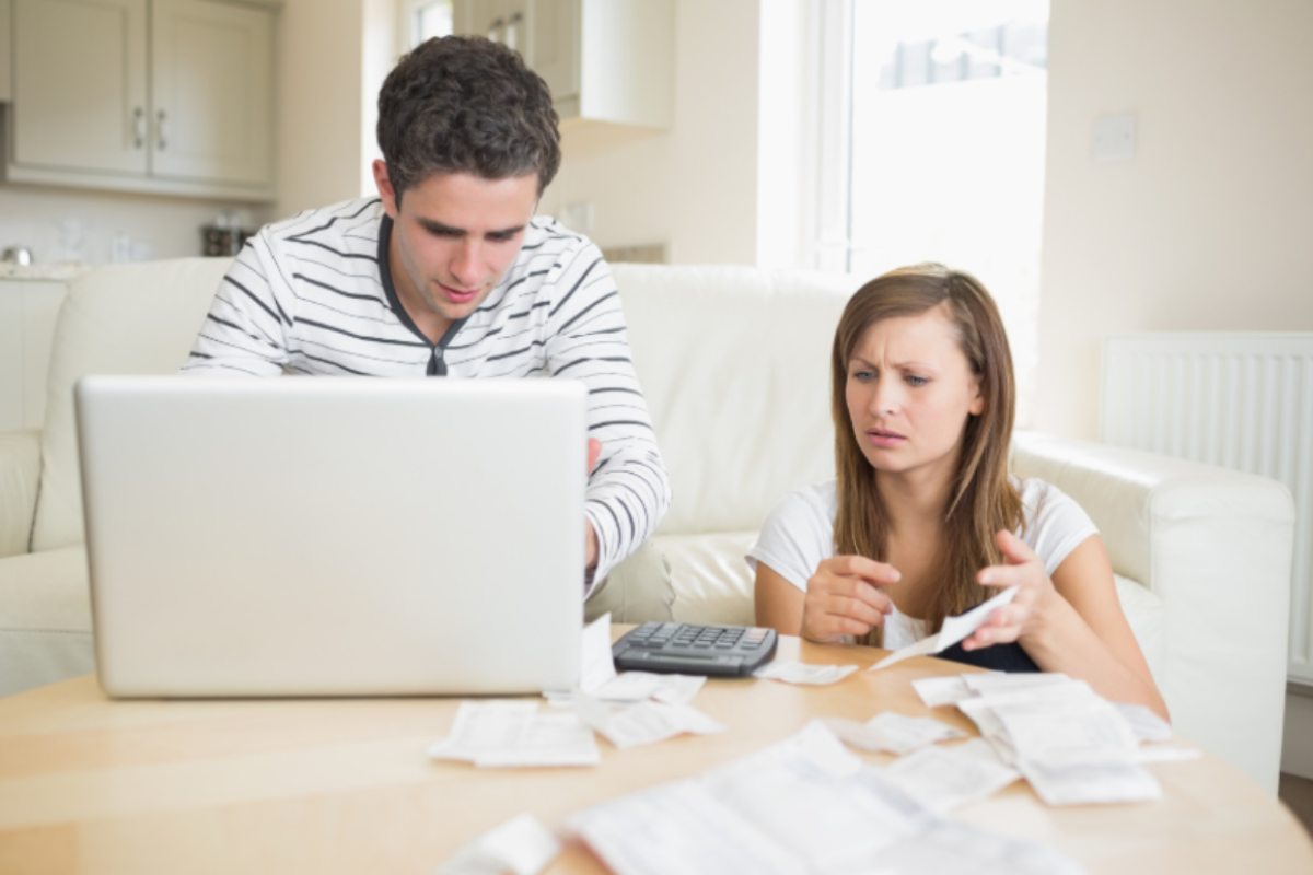 uomo e donna con espressione preoccupata davanti al computer che controllano dei fogli