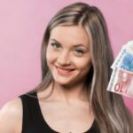 donna che sorride mentre sventola delle banconote che tiene in mano