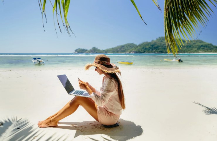 donna che lavora al computer dalla spiaggia