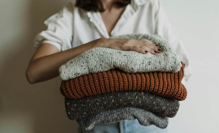 donna con in mano maglioni piegati