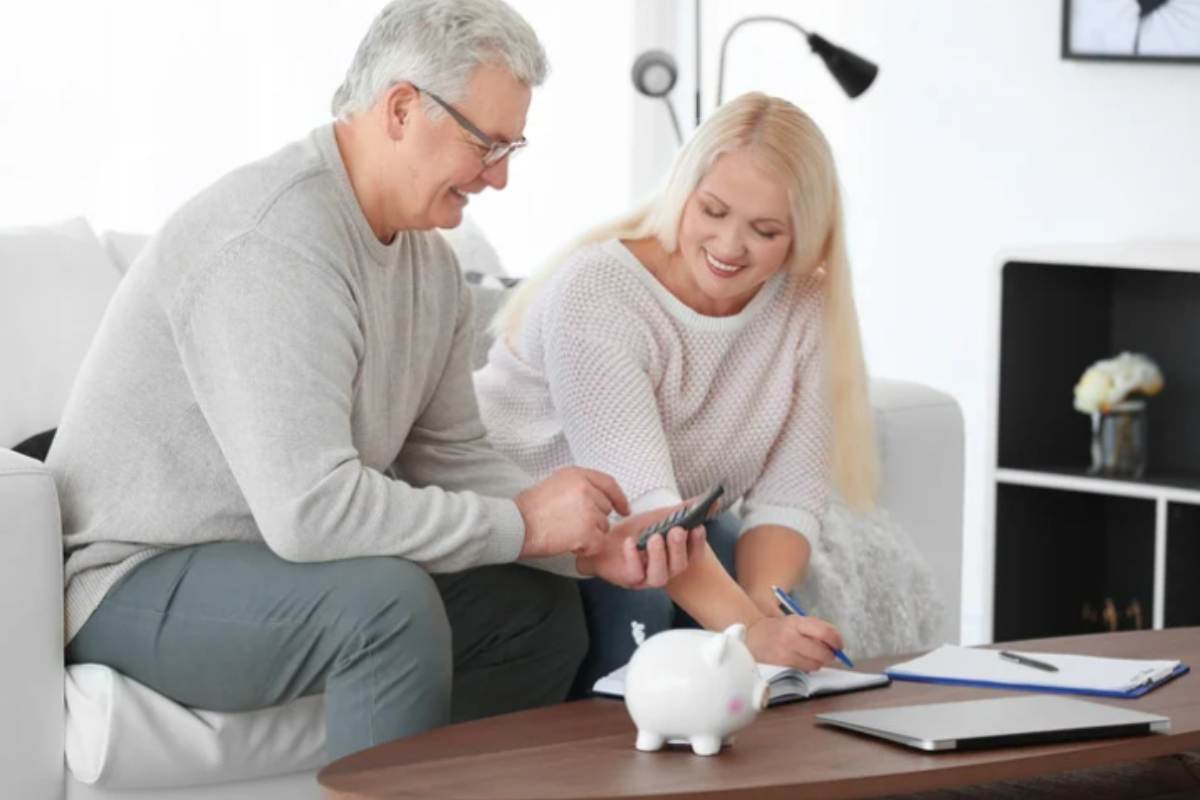 coppia di mezz'età con salvadanaio e calcolatrice
